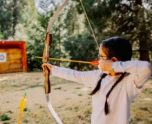 A girl positioning herself to hit the bullseye with her arrow.