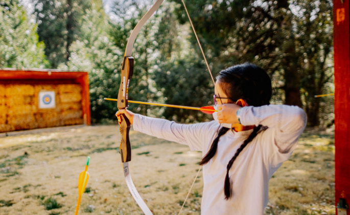 A girl positioning herself to hit the bullseye with her arrow.