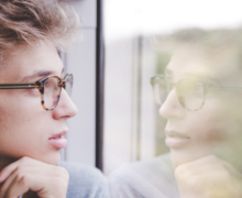 A man looking at his reflection in the glass window