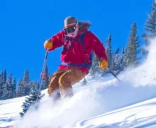 A skier in bright red and yellow attire skiing down a snowy slope.