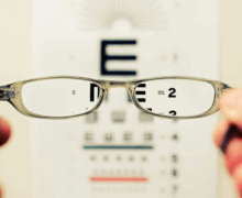 A blurry eye chart viewed through a pair of clear eyeglasses, with the letters coming into sharp focus through the lenses, symbolizing clarity and vision.
