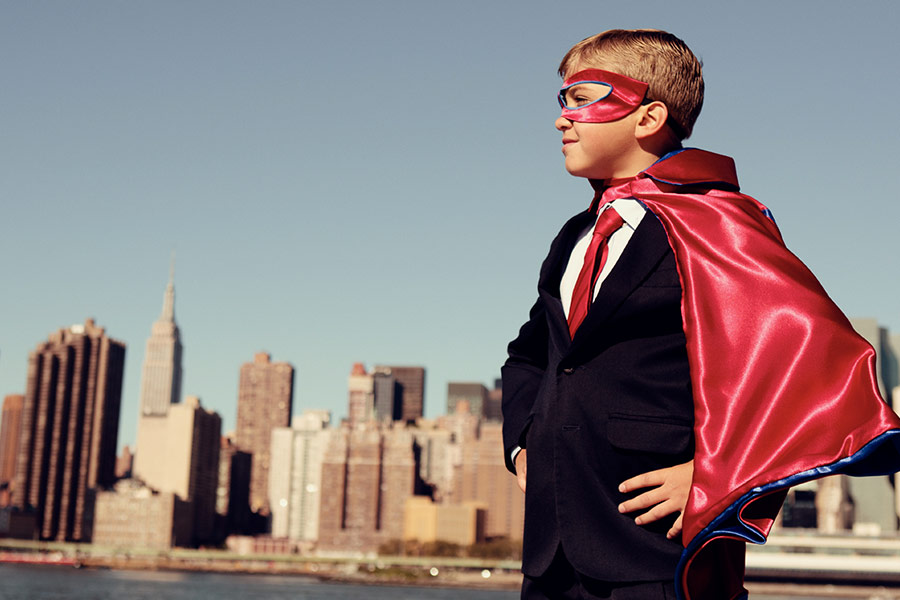 Boy in front of skyline wearing a disguise - cape and mask