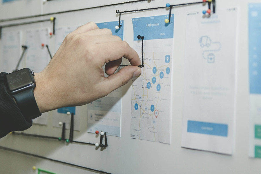 Person mapping out website user flow on pinboard